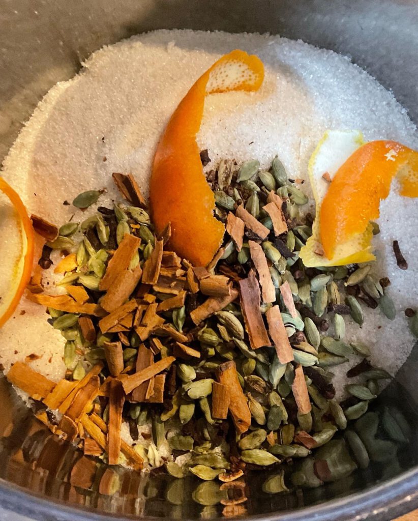 Gewürze, Zucker und Orangenschalen in einem Topf für Chai Sirup