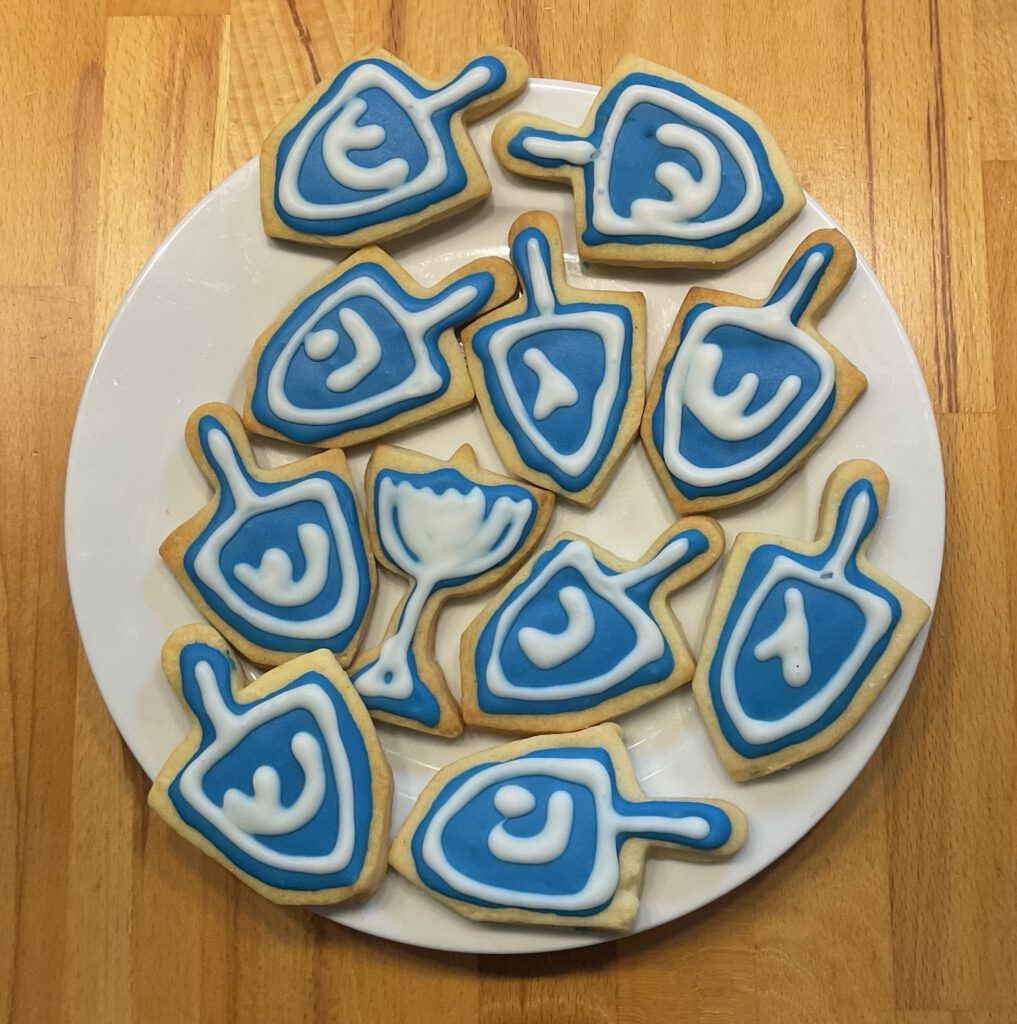 Plätzchen in Dreidel Form und blauer Dekoration.