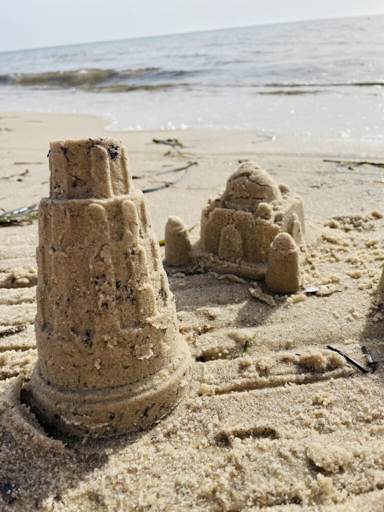 Zwei kleine Sandburgen am Strand.