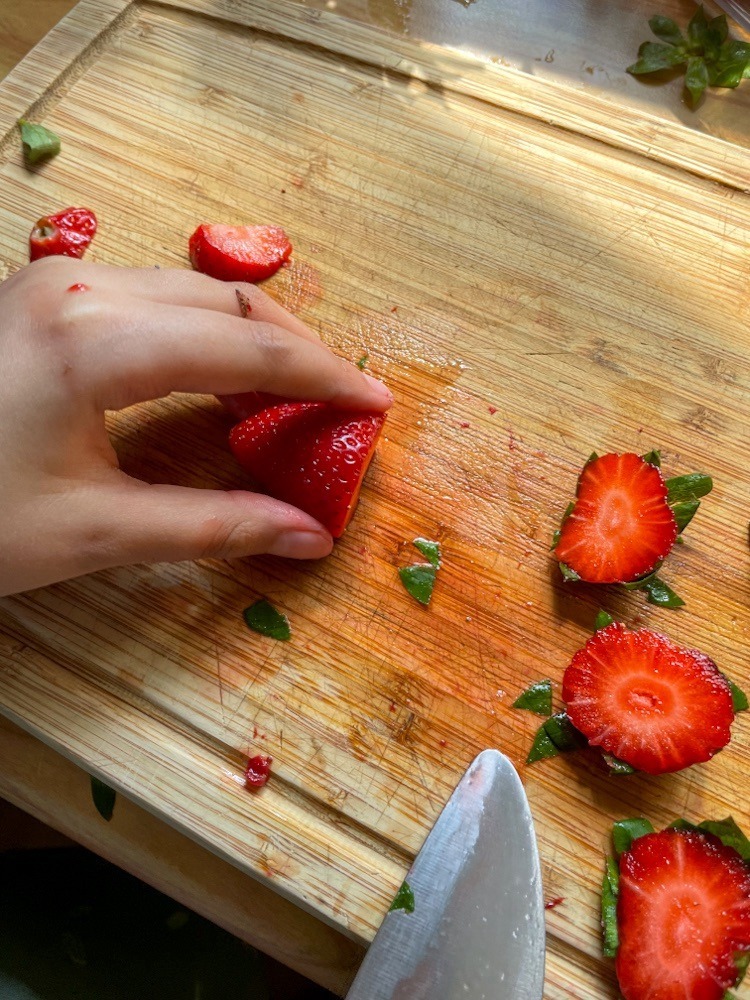 Kinderhände schneiden Erdbeeren.