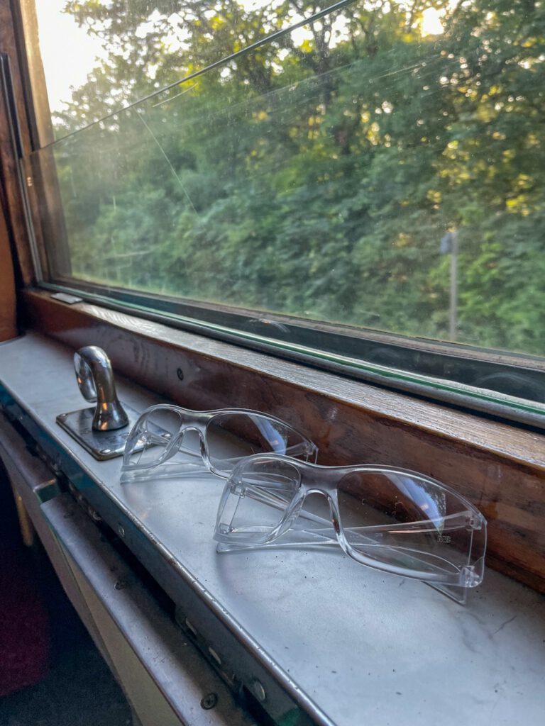Schutzbrillen am Fenster eines historischen Personenwagens.