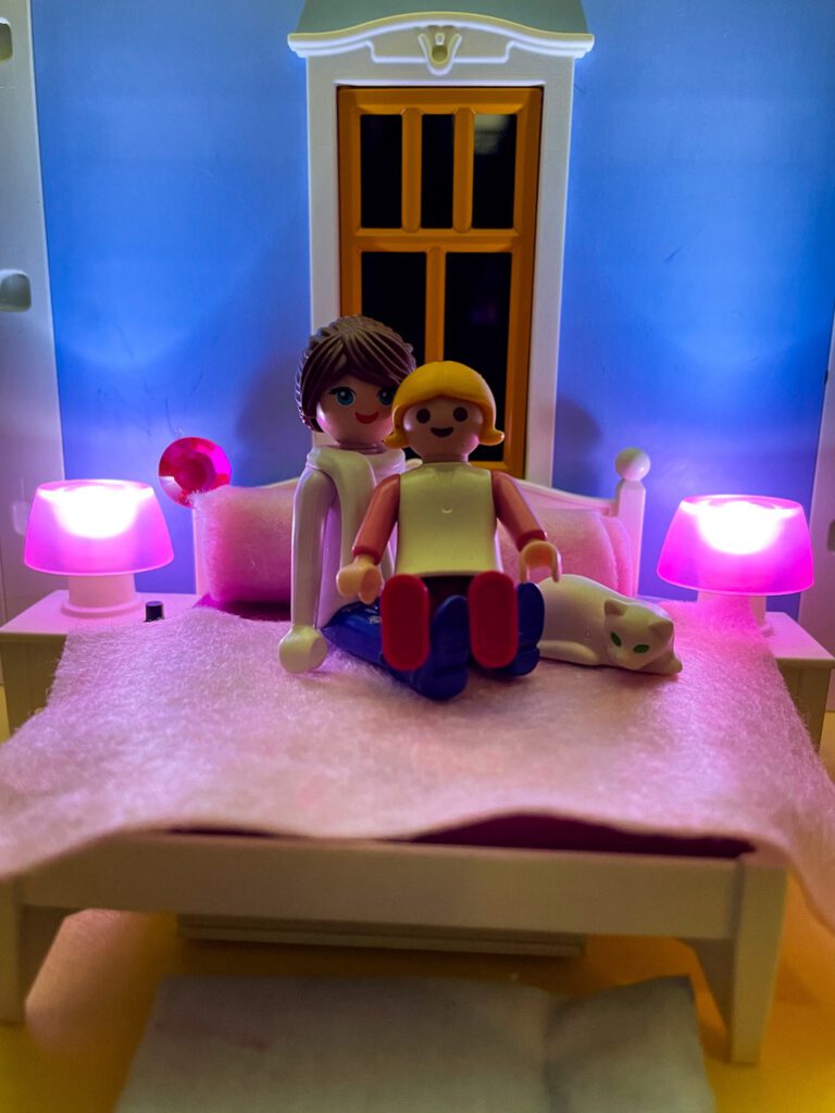 Playmobilfiguren Mama und Kind kuscheln auf dem Bett.