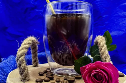 Cold Brew auf Tablett mit Kaffeebohnen und einer Rose.